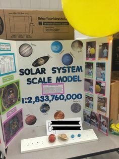 a solar system scale model on display at a science fair with balloons in the background