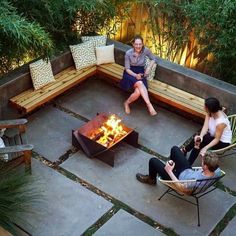 three people sitting around a fire pit in the middle of a patio with chairs and tables