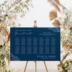 a blue wedding seating plan on an easel in front of flowers and greenery