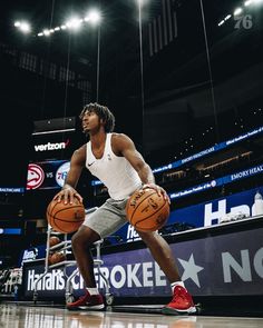 a man holding a basketball while standing on top of a basketball court in front of an arena