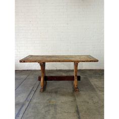 an old wooden table sitting in front of a white brick wall with no one around it