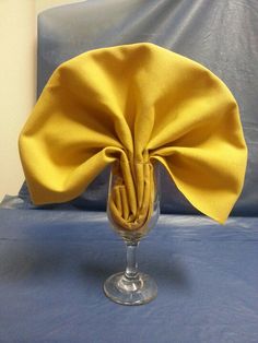 a wine glass with a yellow cloth wrapped around it on top of a blue bed