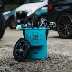 a blue bucket filled with toothbrushes sitting on top of a parking lot