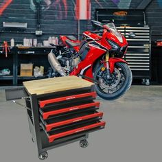 a red motorcycle is parked in front of a tool box with drawers on the side