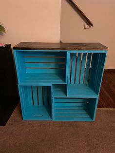 a blue wooden shelf with three sections stacked on top of each other in front of a stair case