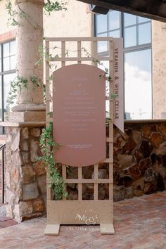 a sign that is sitting in front of a stone building with ivy growing on it