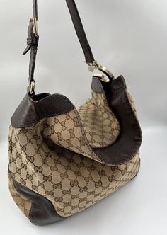 A stunning vintage Gucci hobo bag made from the iconic GG beige canvas with brown leather trim and pale gold hardware. Inside the bag is lined with brown cotton lining and there is a zipped pocket for valuables. This bag is in fair vintage condition with some wear to the leather parts and to the canvas. Gucci Hobo Bag, Pale Gold, Diaper Backpack, Leather Trim, Hobo Bag, Vintage Gucci, Leather Trims, Bag Making, Gold Hardware