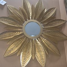 a mirror that is on the side of a wall with gold leaf decorations around it