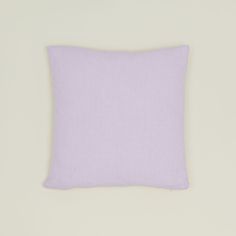 a light purple pillow sitting on top of a white wall