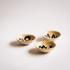 three small bowls with designs on them sitting next to each other in front of a white background