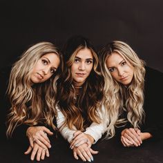 three women are posing for the camera with their hands on each other's shoulders