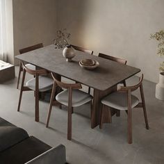 a dining table with four chairs and a vase on it in front of a window