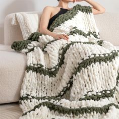 a woman sitting on a couch under a blanket