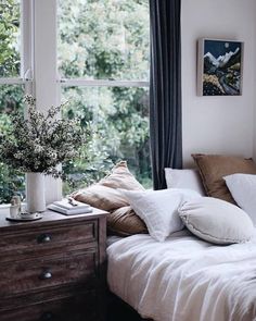 a bed with white sheets and pillows next to a window