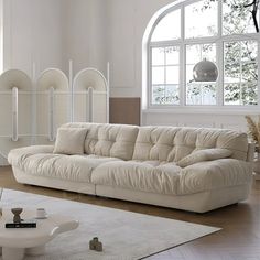 a living room filled with white furniture and large windows in the wall behind it is an arched window