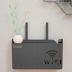 a wall mounted wifi device with a white ball on the top and green streamers coming out of it