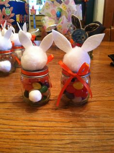 three jars filled with candy and bunny ears on top of a wooden table next to other decorations