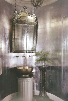 a sink and mirror in a room with a plant on the table next to it