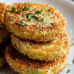 some fried food on a white plate with parsley sprinkled over it's edges