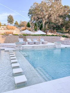 an empty swimming pool with lounge chairs and umbrellas