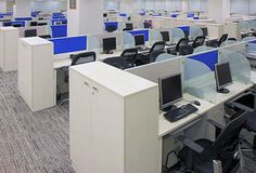 an office cubicle with multiple computers and desks on each side, all in blue and white