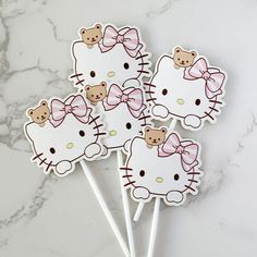 four hello kitty lollipops with bows on them sitting on a marble surface