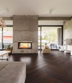 a living room with wood flooring and a fire place in the middle of it