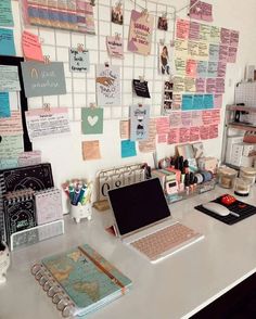 a white desk topped with a laptop computer and lots of notes on the wall behind it