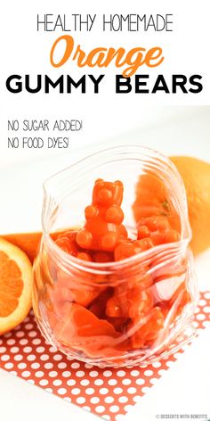 orange gummy bears in a glass bowl next to an orange slice