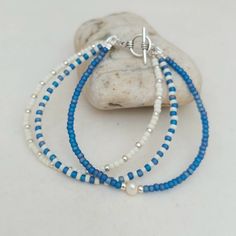 two blue and white beaded bracelets sitting on top of a rock