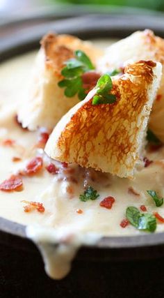 a bowl of soup with bread and garnish on the side, ready to be eaten