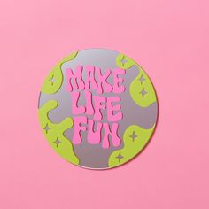 a round sticker with the words make life fun written in pink and green on it