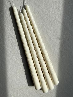 four white candles sitting on top of a table next to each other in the shape of toothpicks