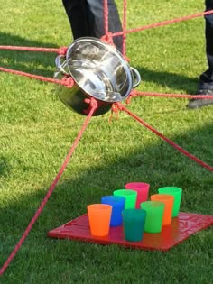 a person standing next to an object in the grass with plastic cups on it and colored blocks