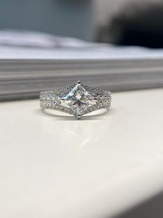 a diamond ring sitting on top of a white table next to a window sill