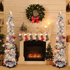 two christmas trees with stockings on them in front of a fireplace