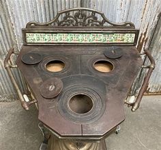 an old fashioned stove sitting on top of a metal stand with two holes in it