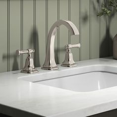 a bathroom sink with two faucets and a vase on the counter next to it