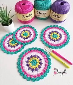 four crocheted doily with yarn next to each other and a plant in the background