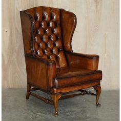 an old fashioned leather chair sitting in front of a wooden wall