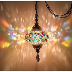 a multicolored glass ball hanging from a chain on a light fixture with colorful lights behind it