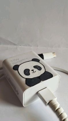 an ipod charger with a panda face on it's side, plugged in