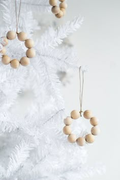 a white christmas tree with wooden beads hanging from it