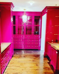 a kitchen with pink cabinets and wood floors in the center is an empty dining room