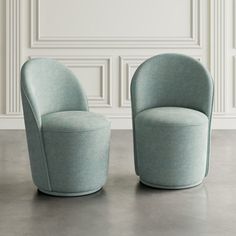 two blue chairs sitting next to each other in a room with white paneled walls