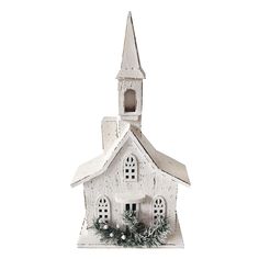 a small white church with a christmas wreath on the front and side of it's steeple