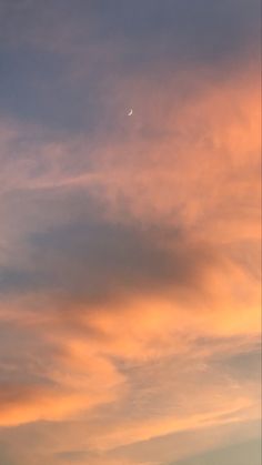 an airplane is flying high in the sky at sunset with clouds and a moon behind it