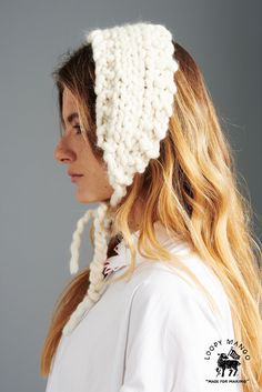 a woman wearing a white knitted hat with braids on her head and long blonde hair