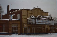 an old movie theater with snow on the ground