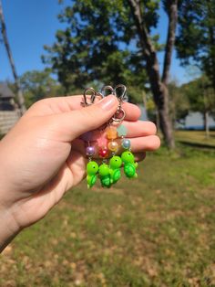 a person is holding several small beads in their hand, with trees in the background